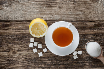 sweet cup of fruit tea with lemon and sugar on a wooden background