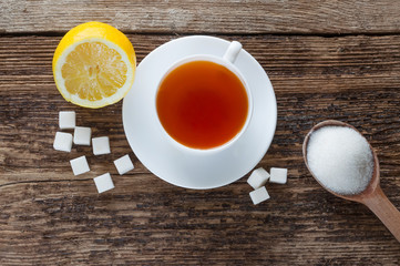 sweet cup of fruit tea with lemon and sugar on a wooden background