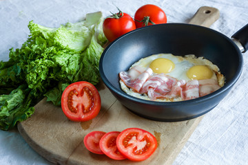 Scrambled eggs and bacon on frying pan on table close-up