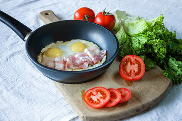 Scrambled eggs and bacon on frying pan on table close-up