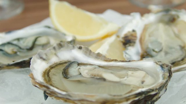 Super close-up of fresh oysters on a white plate with ice. The circular movement of the camera