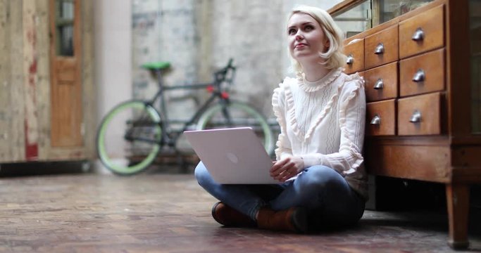 Young adult female sitting on floor working on laptop