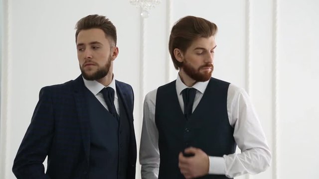 Elegant young bearded handsome men posing in fashionable suits. Studio fashion shooting. Young European hipsters with trendy beards during photo shoot. Guys with fashionable undercuts hairstyle