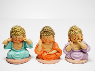 Three little meditating Buddha on white background