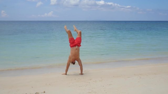 Athletic Man Walking on Hands at the Beach. HD Slow Motion. Koh Phangan, Thailand.