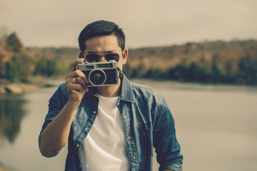 Young man tourist  standing and taking photos with vintage camera.