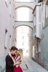 Verliebtes Paar küsst sich in Altstadtgasse mit rotem Kleid