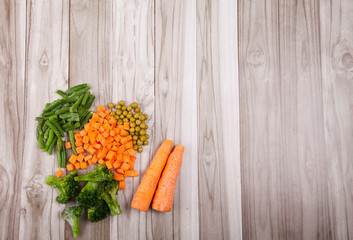 Carrots, broccoli, beans, green pea on a wooden background