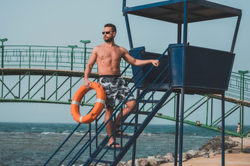 Fototapeta na wymiar bearded lifeguard or muscular man with orange ring buoy