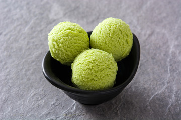 Green tea matcha ice cream scoops on gray stone background
