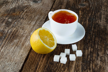 sweet cup of fruit tea with lemon and sugar on a wooden background