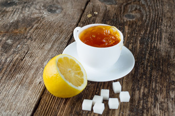 sweet cup of fruit tea with lemon and sugar on a wooden background