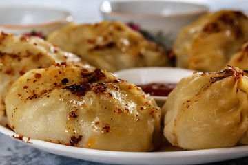 Manti on a plate with sauce. Traditional food of the inhabitants of Central Asia. Closeup