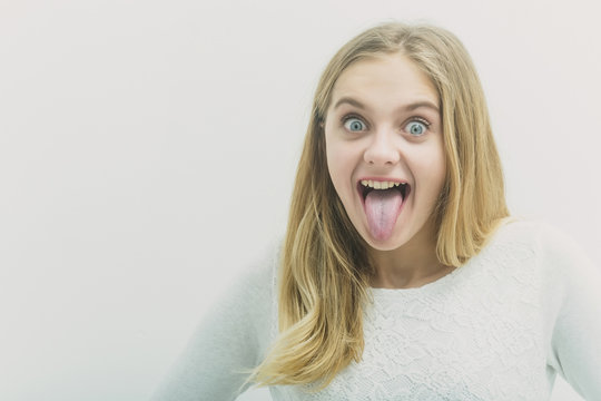 Pretty happy young girl with blond hair showing tongue