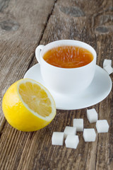 sweet cup of fruit tea with lemon and sugar on a wooden background