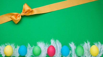 Easter green frame with eggs, ribbon and feather. Top view
