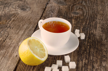 sweet cup of fruit tea with lemon and sugar on a wooden background