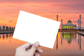 Hand holding the empty photo with mosque in the background.