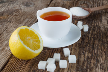 sweet cup of fruit tea with lemon and sugar on a wooden background