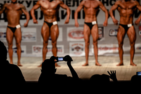 blurred bodybuilders on stage view from dark auditorium in bodybuilding competitions