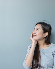 Closeup asian woman sitting and look at space with smile face on blurred cement wall textured background with copy space