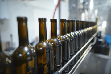 Row of glass wine bottles moving by conveyor