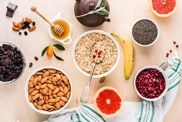Ingredients for a healthy breakfast: oatmeal, honey, fruits,berries, grapefruit, chia seeds, almonds, raisins, banana and herbal tea. The concept of natural organic food in season. Top view