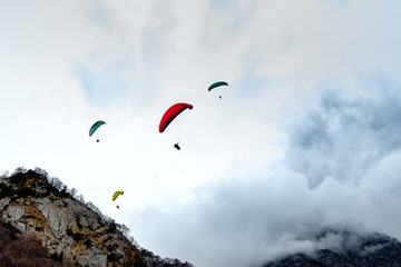 Flying paraglider in the clouds on a background of mountains.