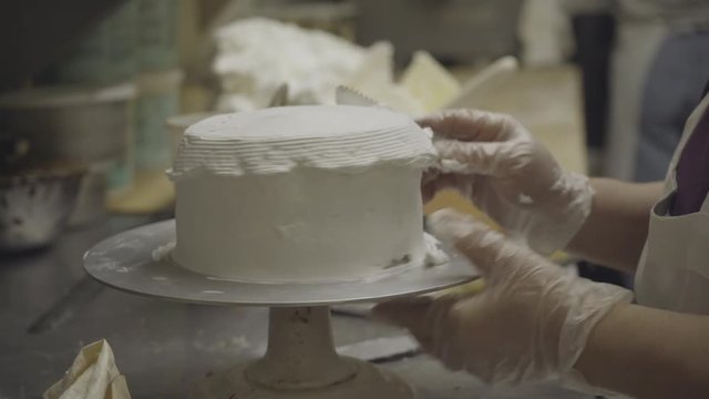 Baker applies texture frosting of round cake
