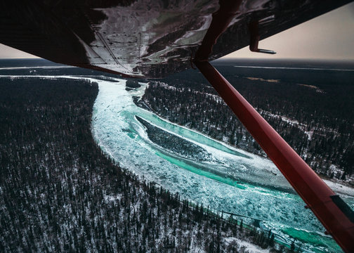 Frozen river and woodland reflected on air craft wing, Alaska, United States of America 