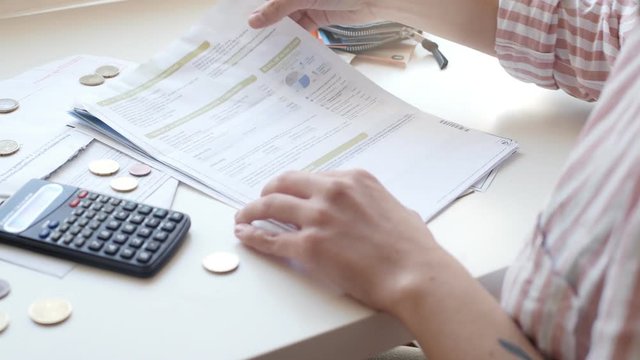 Woman hands is using scietific calculator to check total sum of household bills
