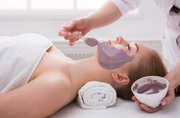 Woman gets face mask by beautician at spa