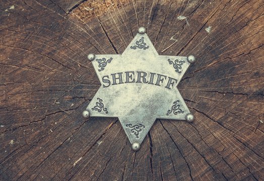 Sheriff badge on wooden background. Macro shot.