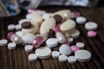 pile of pills of different sizes on a wooden background