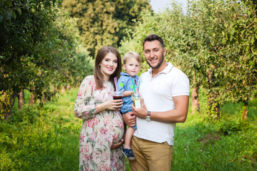 Fototapeta premium Young attractive family walking in a meadow and drinking juice