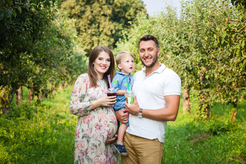 Fototapeta premium Young attractive family walking in a meadow and drinking juice