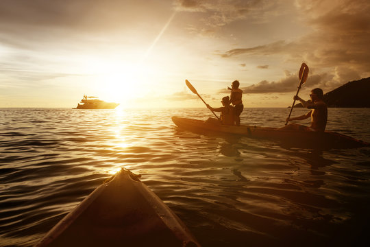 Two kayaks with family at sunset sea