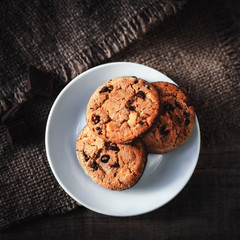 Chocolate chip cookies on white plate dark old wooden table with place for text.,  freshly baked. Selective Focus with Copy space..