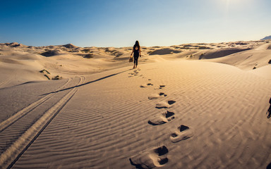 Fototapeta na wymiar Girl walking into a sand desert, Mexico