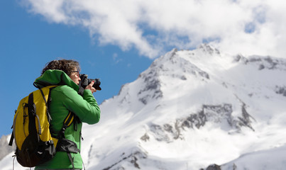 Fototapeta na wymiar Hiker with camera and backpack taking picture of beautiful mountain