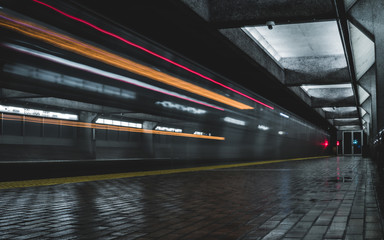Subway station with passing subway at night