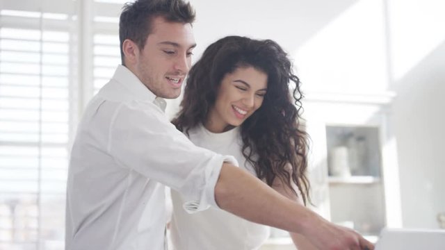  Happy affectionate couple relaxing at home, looking at laptop computer