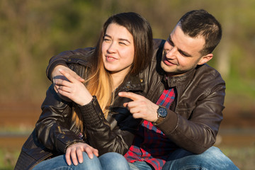 Loving couple sitting on the railroad. Both point the finger.