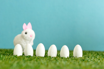 A row of white easter eggs with a fluffy bunny that is out of focus