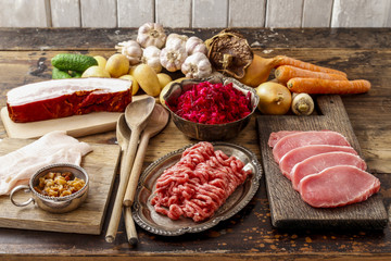 Different kinds of meat and vegetables on wooden table.