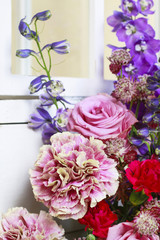 Floral arrangement with pink roses, carnations and delphinium flowers.