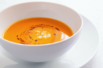 a bowl of pumpkin cream soup decorated with bryndza cheese and pumpkin oil