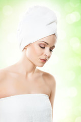 Portrait of young, beautiful woman with bath towel on her head: over green background. Healthcare, spa, makeup and face lifting concept.