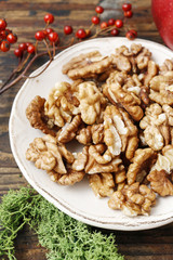 Bowl of walnuts and red apples on wooden table