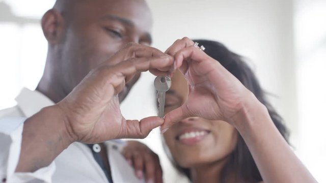  Happy romantic couple with key to new home make heart shape with their hands